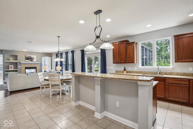 kitchen featuring light stone countertops, sink, a wealth of natural light, and decorative light fixtures