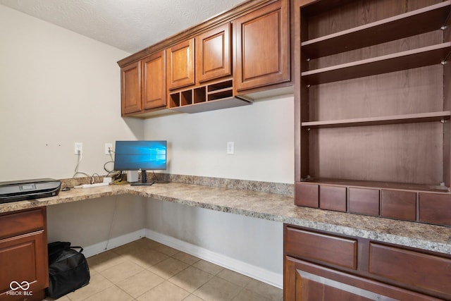 kitchen featuring light tile patterned floors, built in desk, and a textured ceiling