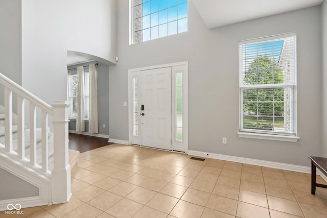 foyer entrance with light tile patterned floors and a towering ceiling