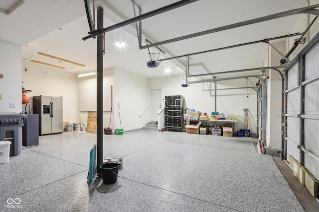 garage featuring a garage door opener and stainless steel fridge with ice dispenser