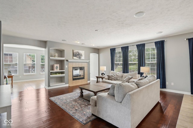 living room featuring dark hardwood / wood-style flooring, a fireplace, built in features, and a textured ceiling