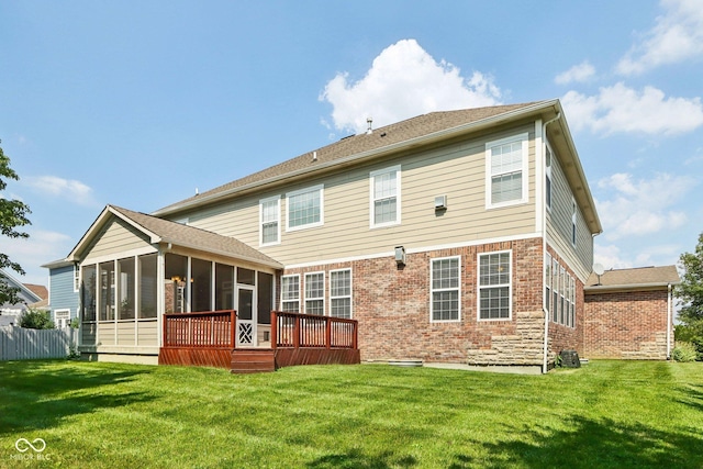 rear view of property featuring a wooden deck, a yard, and a sunroom