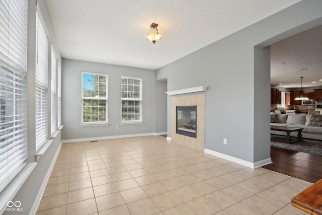 unfurnished living room featuring a tiled fireplace and light tile patterned flooring