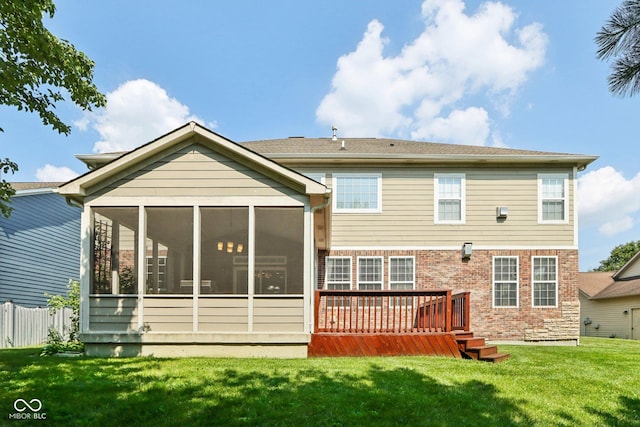 rear view of house featuring a wooden deck, a sunroom, and a lawn