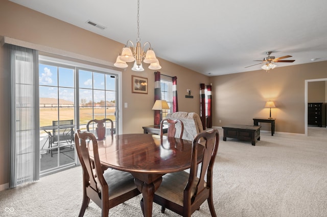 carpeted dining space featuring ceiling fan with notable chandelier