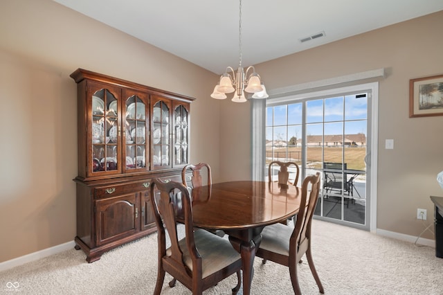 carpeted dining area featuring an inviting chandelier