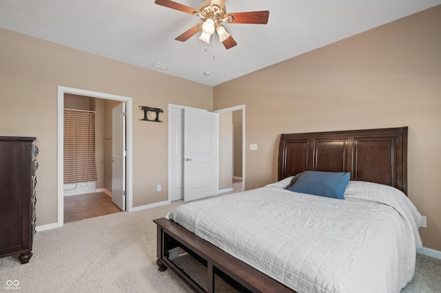 bedroom with ceiling fan, light colored carpet, and ensuite bath