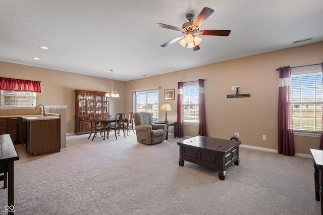 living room with light carpet, sink, ceiling fan with notable chandelier, and plenty of natural light