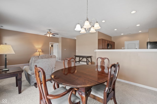 carpeted dining room featuring ceiling fan with notable chandelier