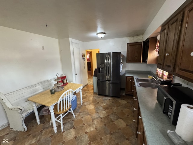 kitchen with sink, stainless steel fridge, and dark brown cabinetry