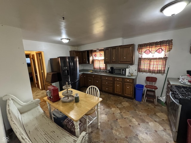 kitchen with stainless steel gas stove, dark brown cabinetry, and black fridge