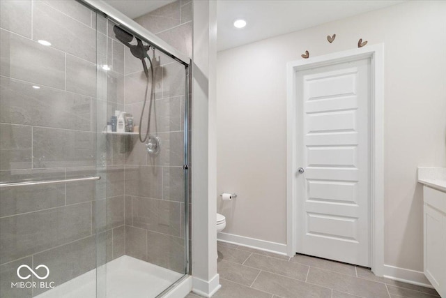 bathroom featuring a shower with door, vanity, tile patterned floors, and toilet