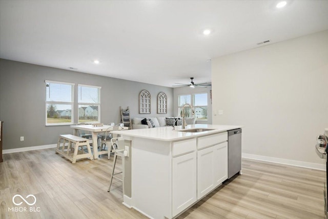 kitchen featuring sink, white cabinets, stainless steel dishwasher, a center island with sink, and light wood-type flooring