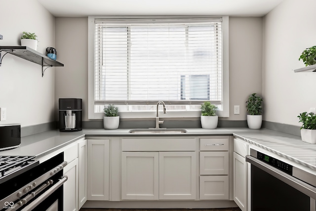 kitchen with stainless steel gas stove, sink, and white cabinets