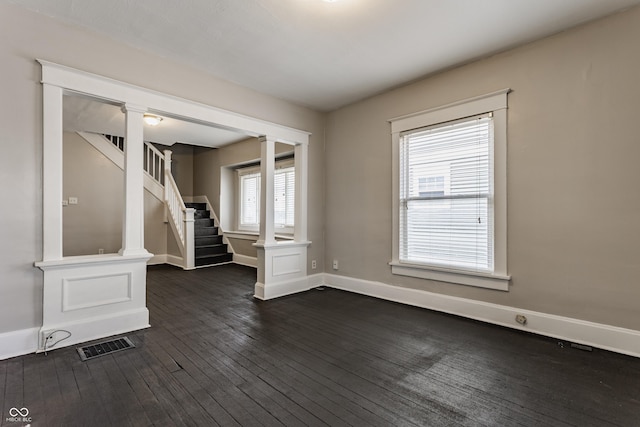 empty room with dark hardwood / wood-style floors and ornate columns