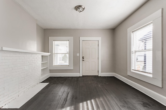 foyer with dark wood-type flooring, plenty of natural light, and a textured ceiling