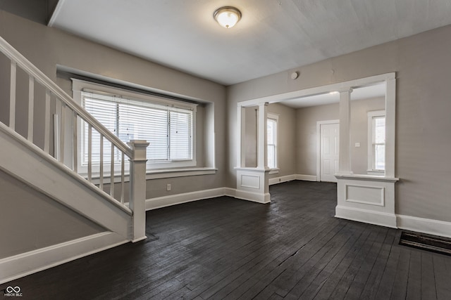 interior space with decorative columns and dark hardwood / wood-style floors