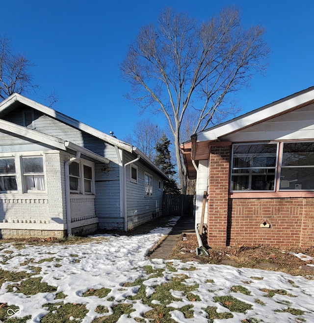 snow covered property with brick siding