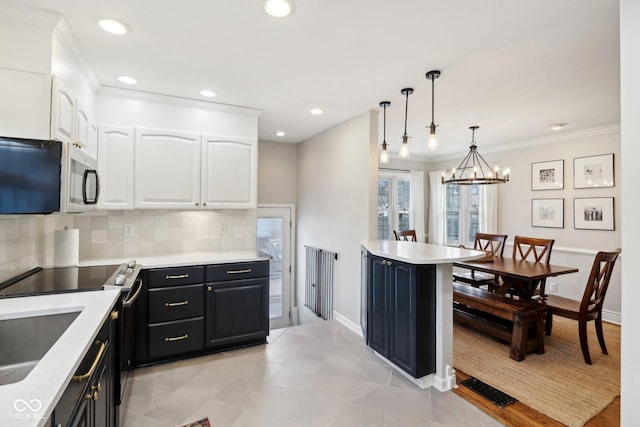 kitchen featuring decorative light fixtures, white cabinets, backsplash, ornamental molding, and stainless steel appliances