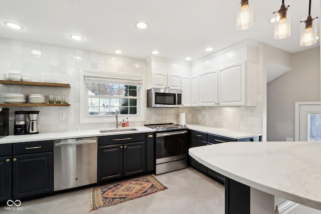 kitchen with sink, white cabinetry, decorative light fixtures, appliances with stainless steel finishes, and decorative backsplash