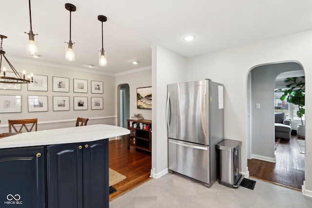 kitchen featuring ornamental molding, blue cabinetry, stainless steel refrigerator, and decorative light fixtures