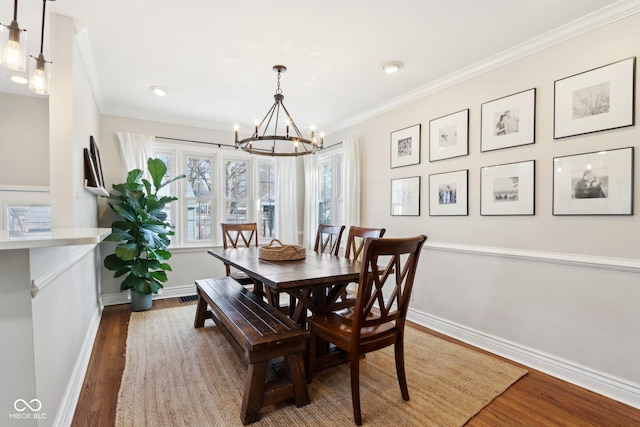 dining room with an inviting chandelier, ornamental molding, and hardwood / wood-style floors