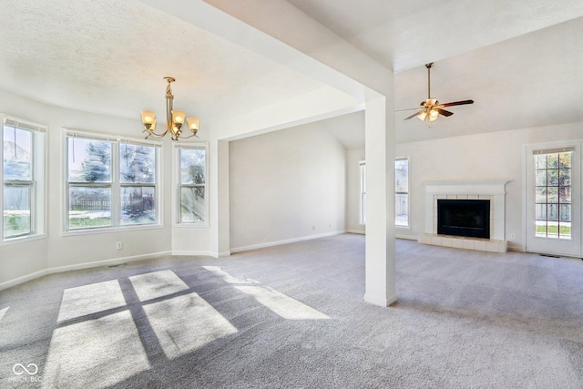 unfurnished living room with vaulted ceiling, a tile fireplace, carpet, and ceiling fan with notable chandelier