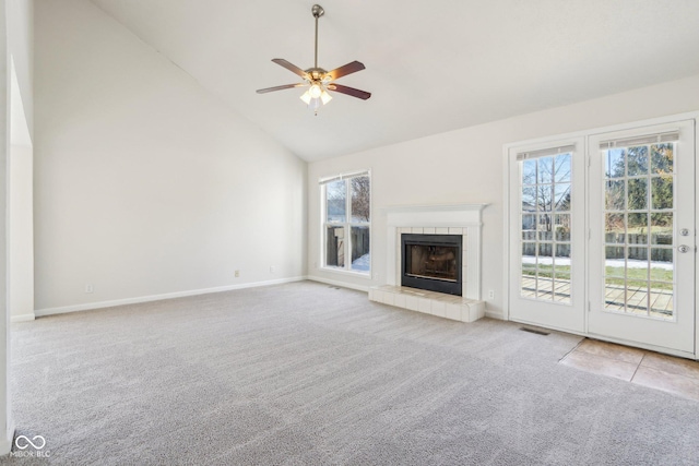 unfurnished living room with ceiling fan, light colored carpet, a tiled fireplace, and high vaulted ceiling