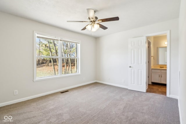 unfurnished bedroom with carpet floors, connected bathroom, and ceiling fan