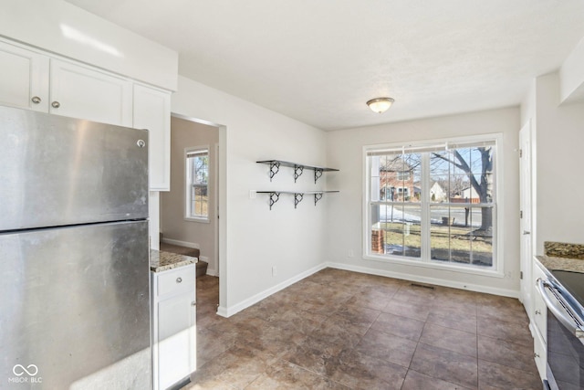 kitchen with stainless steel appliances, dark stone counters, and white cabinets