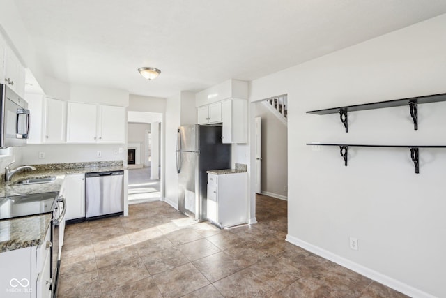 kitchen featuring appliances with stainless steel finishes, sink, dark stone counters, and white cabinets