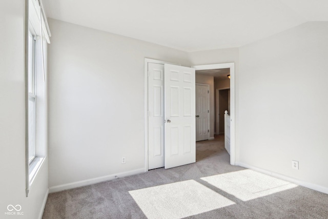 unfurnished bedroom featuring light colored carpet and vaulted ceiling