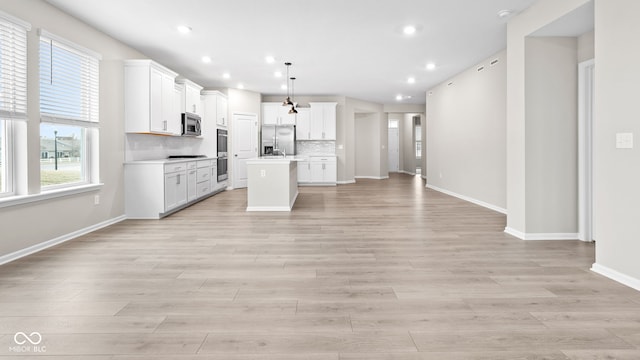 kitchen with stainless steel appliances, white cabinetry, a center island, and pendant lighting