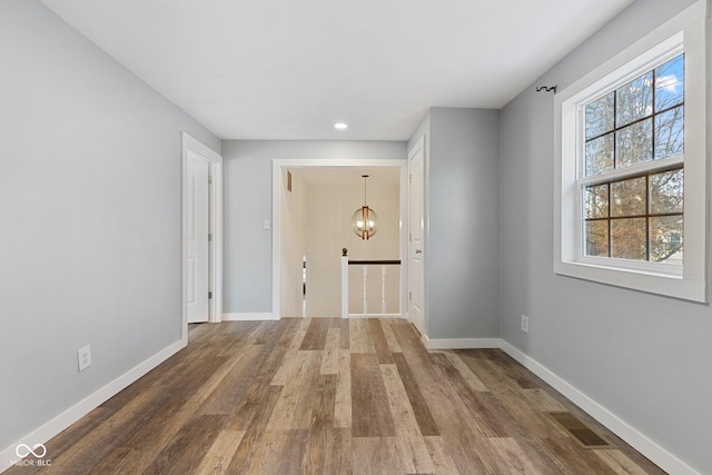 corridor with hardwood / wood-style flooring and a chandelier