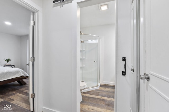 bathroom featuring toilet, an enclosed shower, and hardwood / wood-style floors