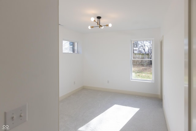 unfurnished room with a healthy amount of sunlight, light carpet, and a notable chandelier