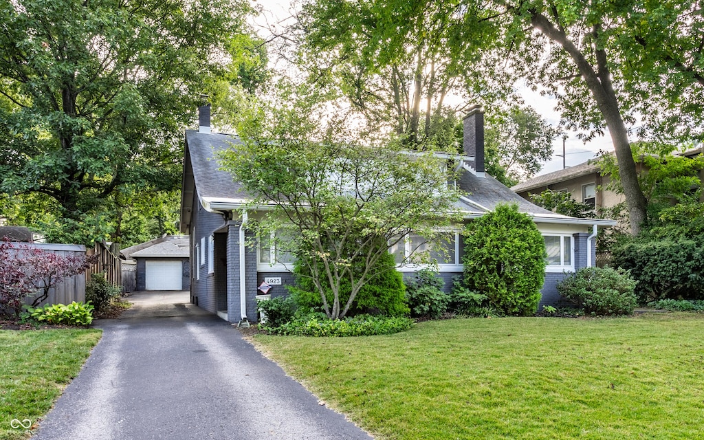 obstructed view of property featuring a garage, an outbuilding, and a front yard