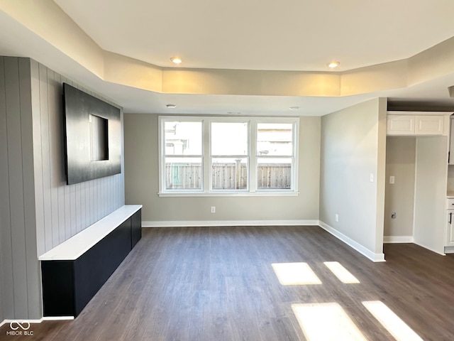 unfurnished living room with dark hardwood / wood-style flooring and a raised ceiling