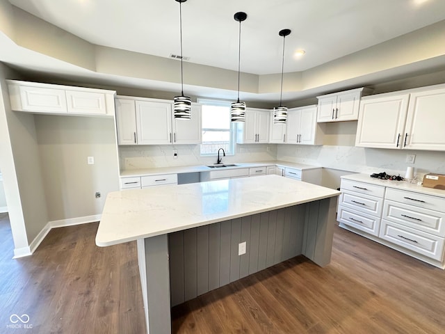 kitchen with white cabinetry, hanging light fixtures, light stone counters, and a center island