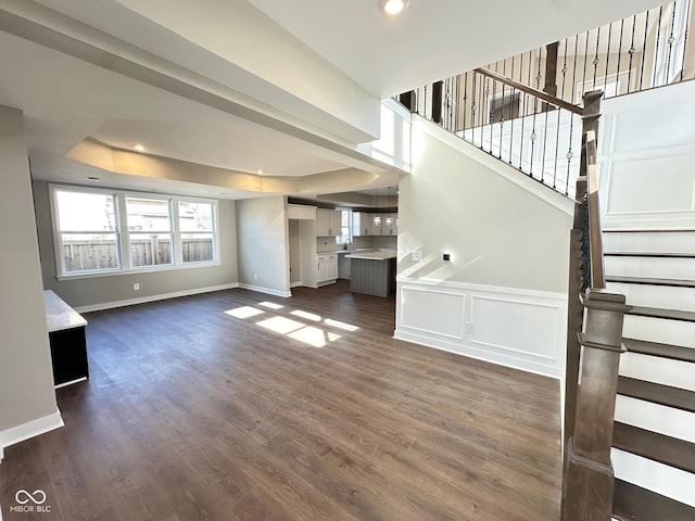 unfurnished living room with dark hardwood / wood-style flooring and a raised ceiling