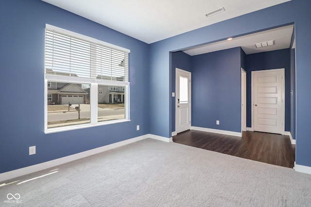 spare room featuring visible vents, carpet flooring, and baseboards