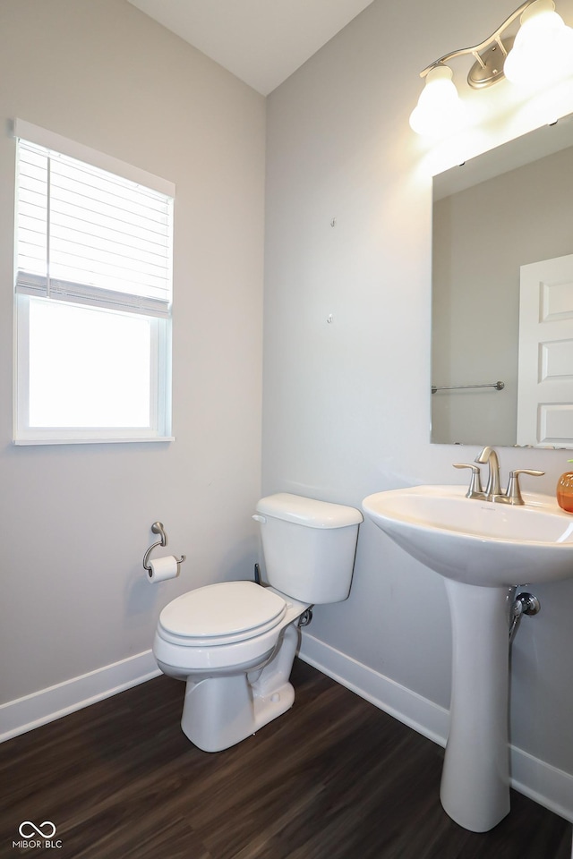 half bath with a sink, toilet, baseboards, and wood finished floors