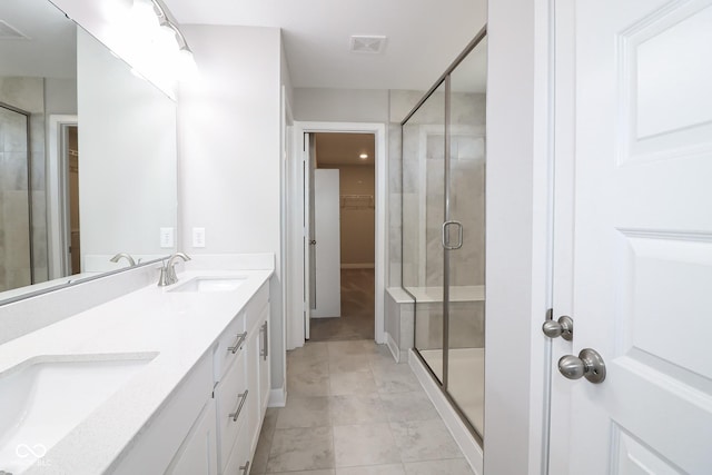 full bathroom with a sink, visible vents, a walk in closet, and a shower stall