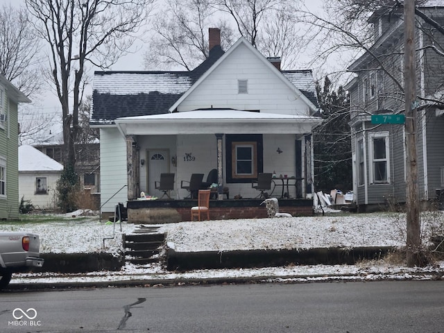 bungalow-style house with a porch, a chimney, and a shingled roof