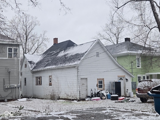 snow covered house featuring a chimney