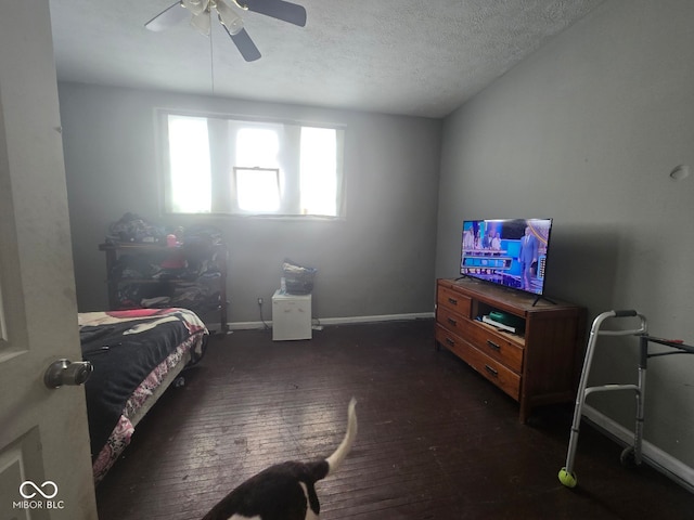 bedroom with dark wood finished floors, ceiling fan, a textured ceiling, and baseboards