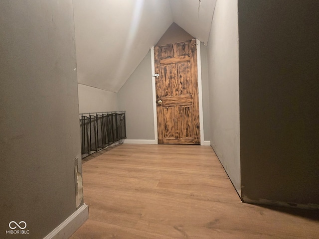 additional living space with lofted ceiling, light wood finished floors, and baseboards