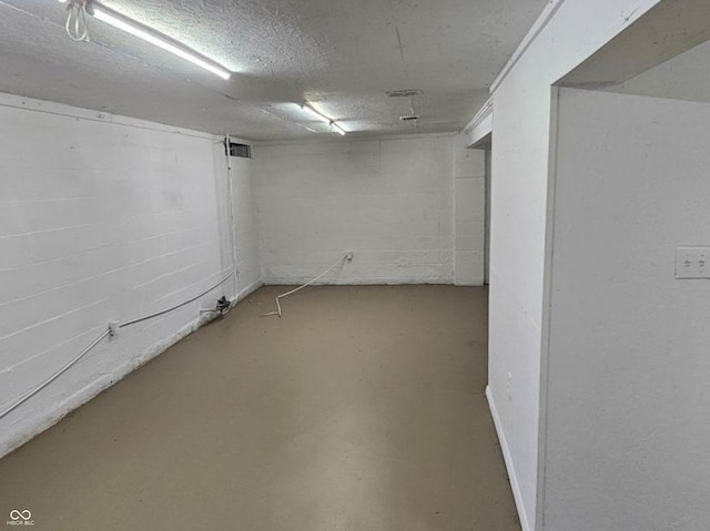 finished below grade area featuring concrete block wall and a textured ceiling