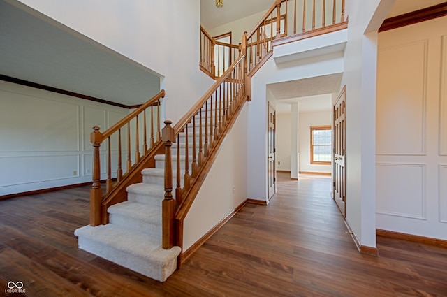 stairs featuring a towering ceiling and hardwood / wood-style floors