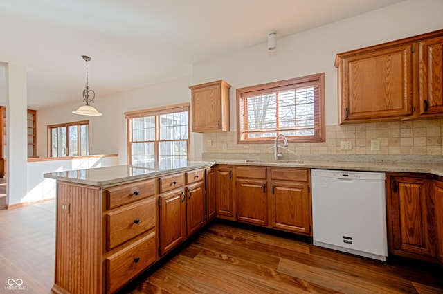 kitchen with white dishwasher, sink, pendant lighting, and kitchen peninsula